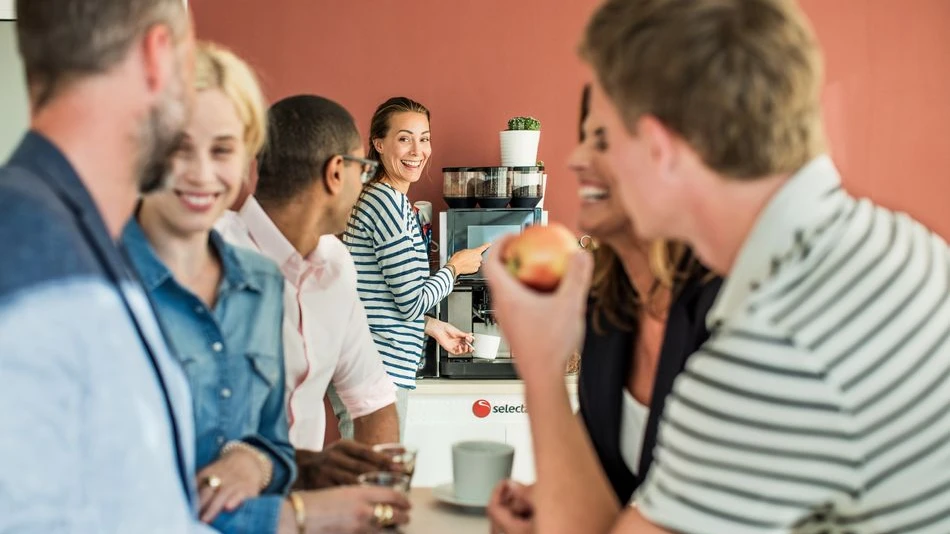 A group of people enjoying office coffee made with a tabletop coffee machine